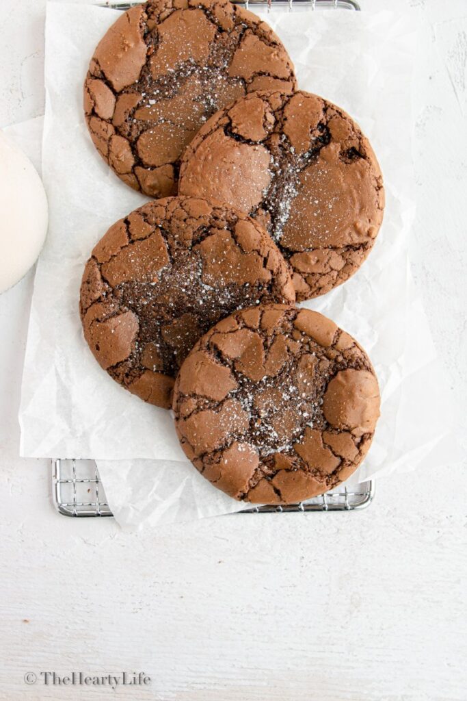 brownie cookies lined on a cooling rack with parchment paper and a glass of milk