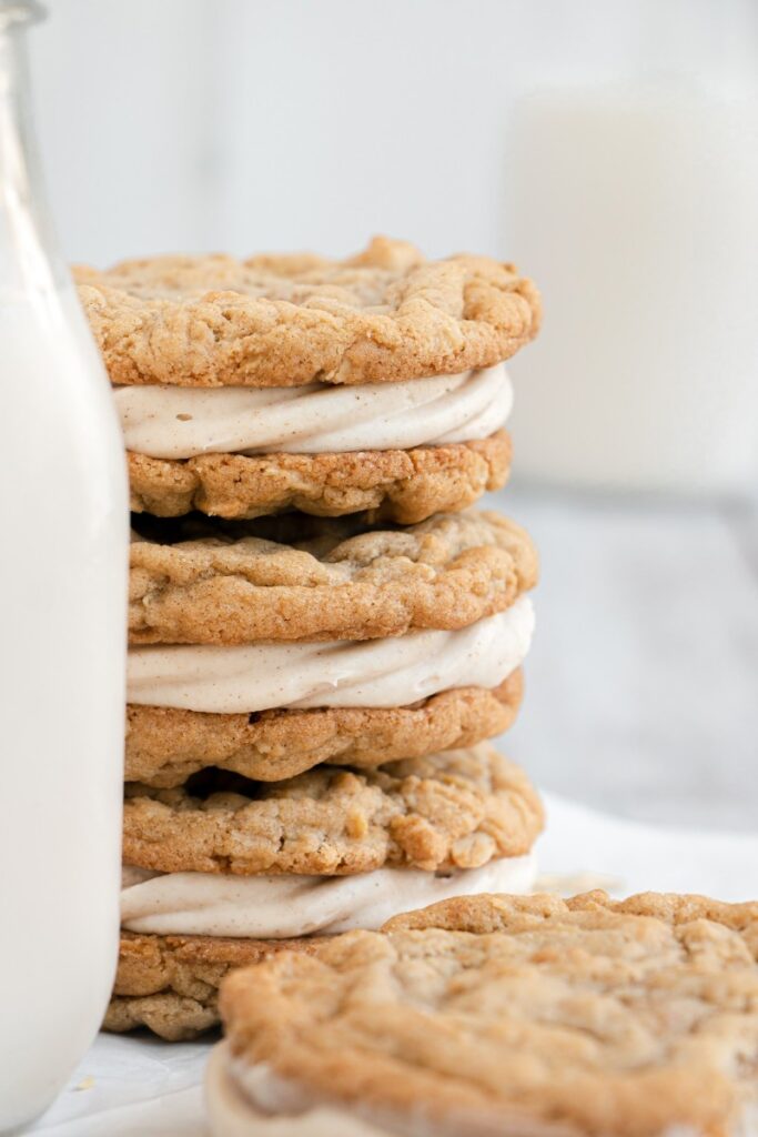 sandwich cookies stacked with a glass of milk