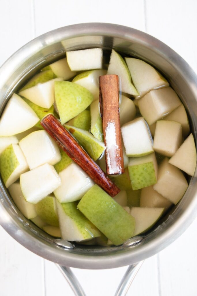sauce pan with pears, sugar, and cinnamon sticks