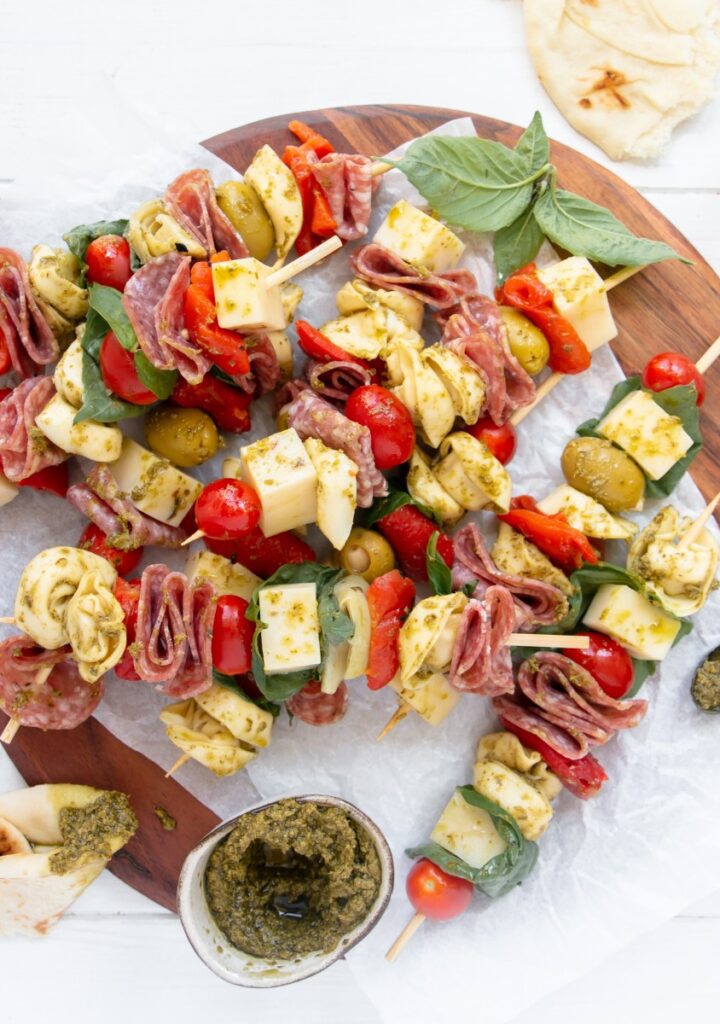 serving platter with skewers stacked and bowls of pesto
