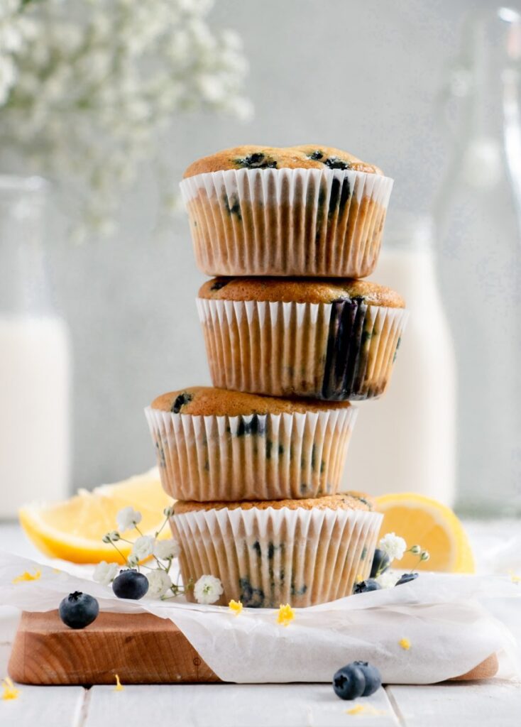 stack of muffins on a cutting board with flowers and lemon wedges