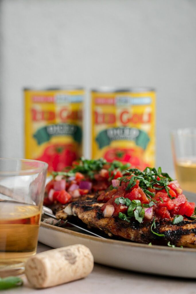 side photo of bruschetta chicken with red gold tomatoes in the background