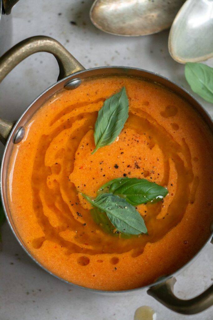 soup in a pot with basil oil and fresh basil
