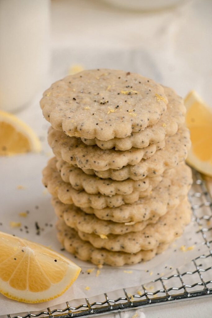 stacked lemon poppy seed cookies on cooling rack with lemon wedge 