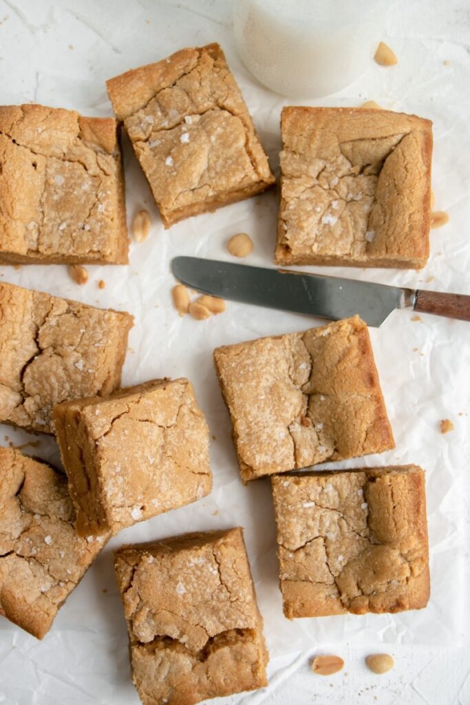 sliced blondies, next to a knife, and cup of milk