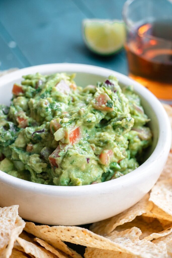 bowl of guacamole with chips on side
