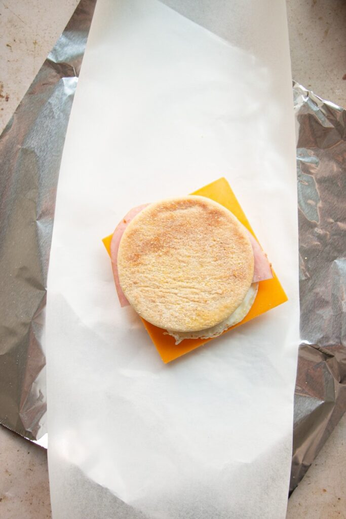 assembled breakfast sandwich wrapped in parchment paper and aluminum foil