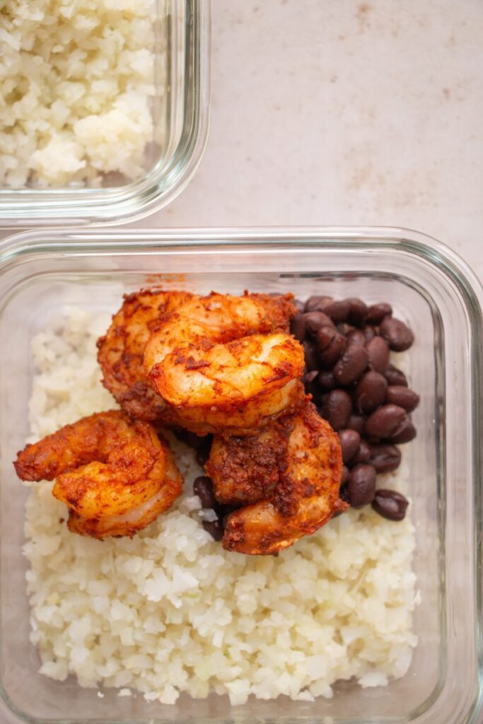 glass container with cauliflower rice, black beans, and shrimp