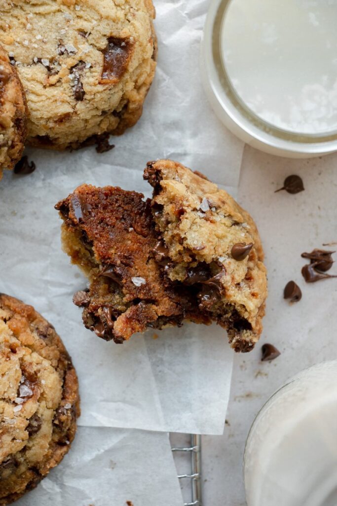 hot, gooey salted toffee chocolate chip cookie torn in half on parchment paper