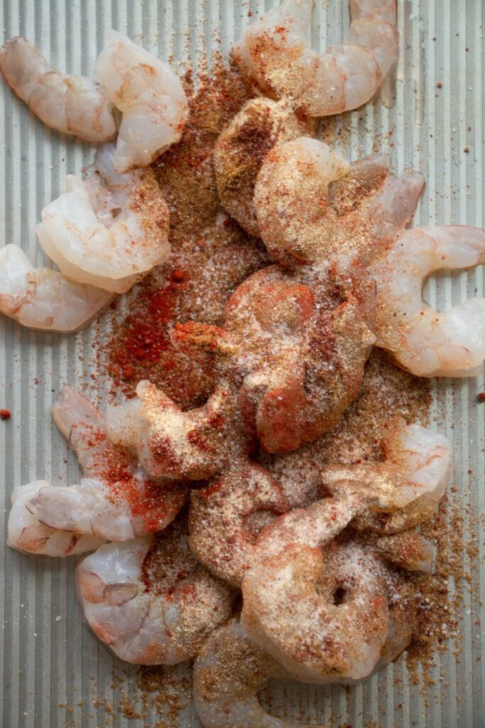 raw shrimp on a sheet pan with seasoning