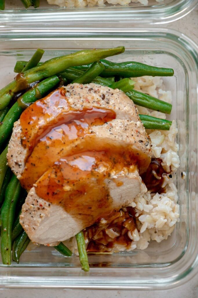 pork topped with honey soy sauce over rice and green beans 