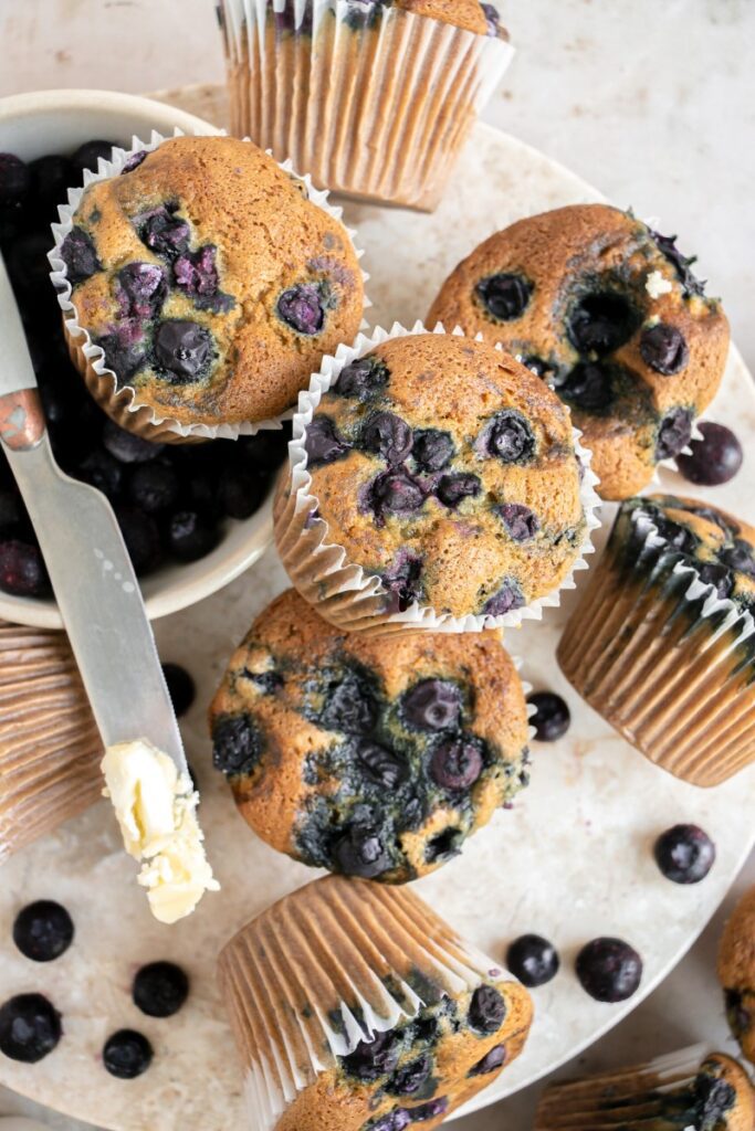 tray full of blueberry muffins and a butter knife with butter