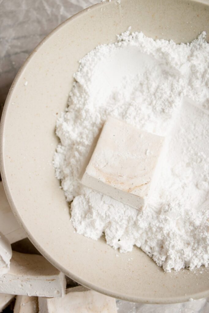 homemade vanilla bean marshmallows in a bowl of powdered sugar
