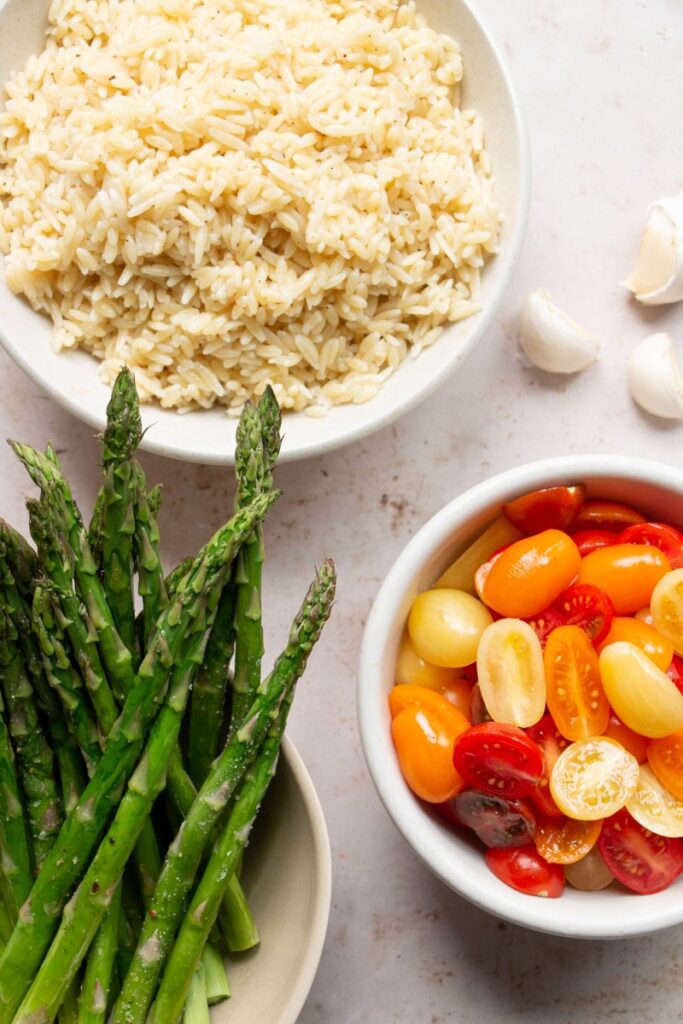 bowls of orzo, whole asparagus, and cherry tomatoes 