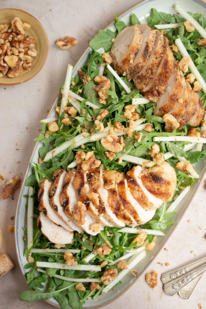 Arugula, Apple, and Walnut Salad with Grilled Chicken on a platter