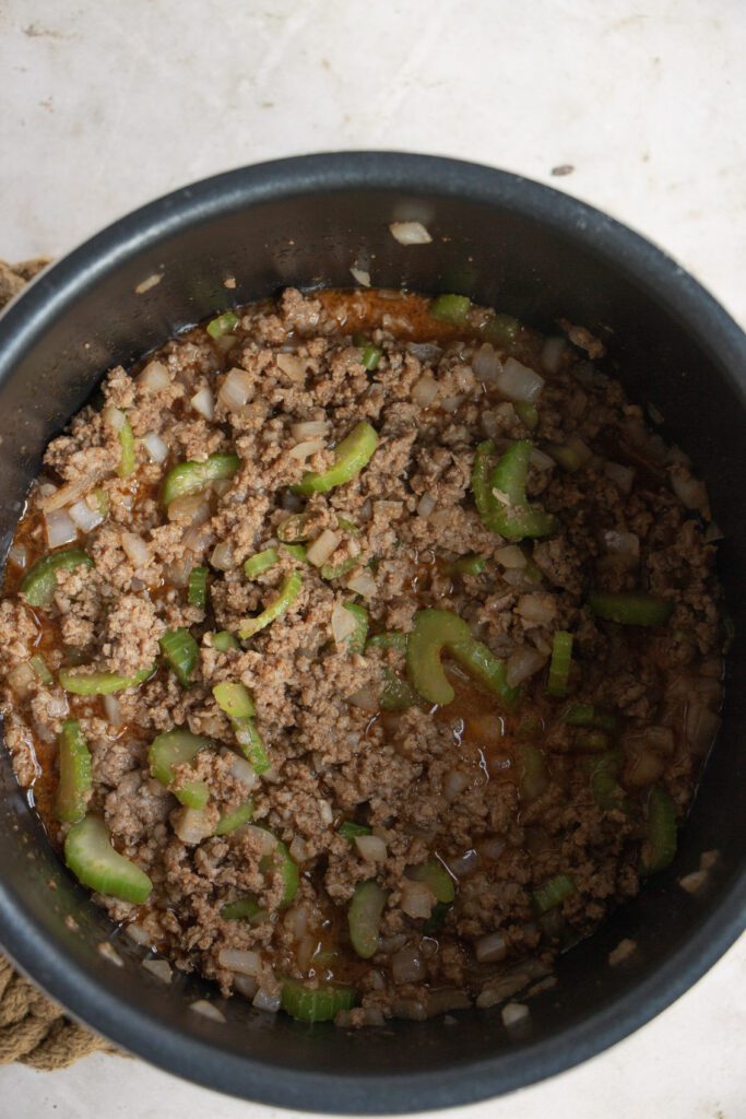 beef, celery, onions cooking in the base of an instant pot 