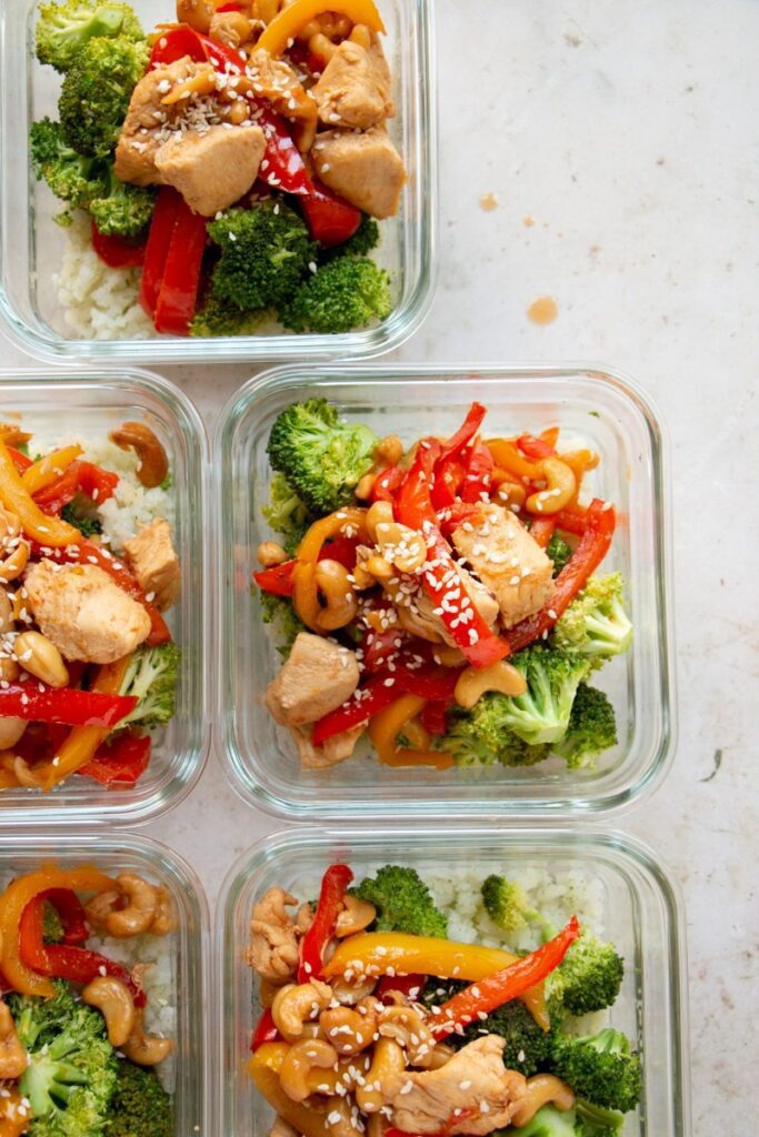 5 meal prep bowls with cashew chicken topped with sesame seeds