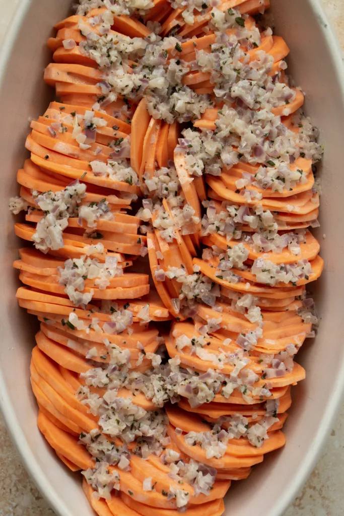 casserole dish lined with sweet potatoes  topped with cream sauce 
