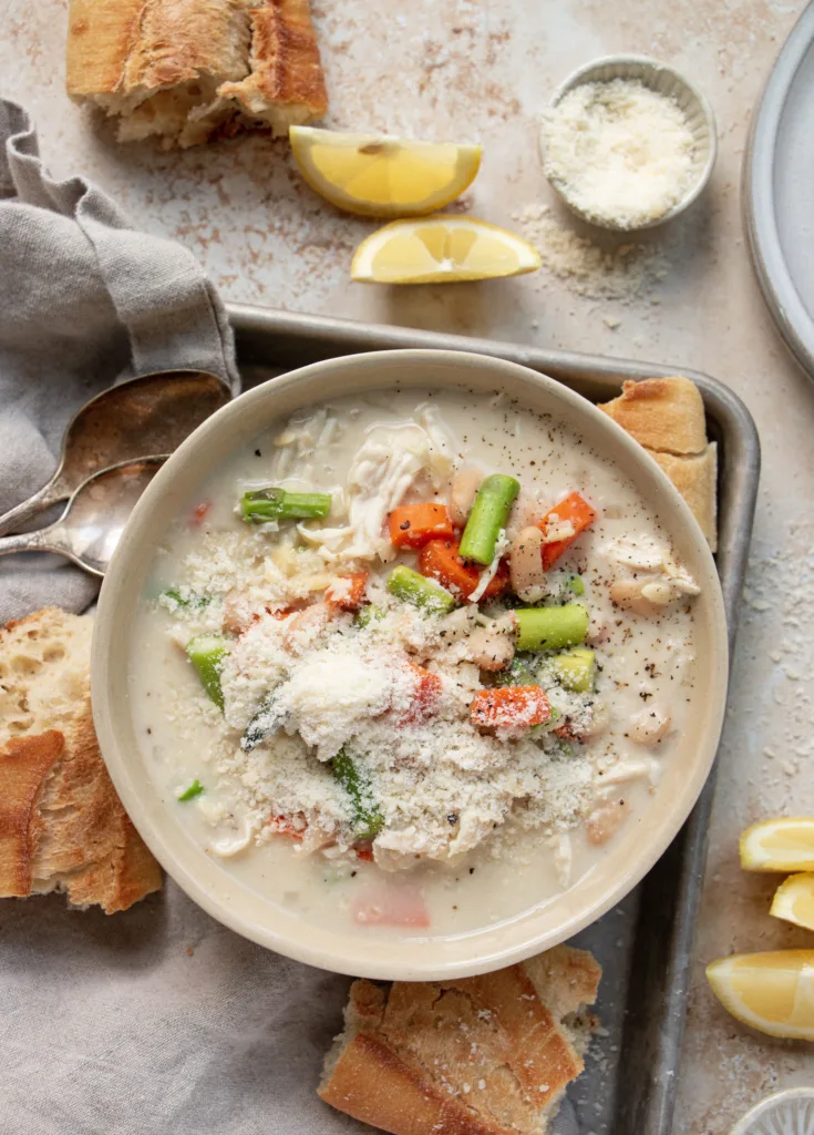 bowl of slow cooker lemon orzo chicken soup with crispy bread and parmesan cheese 