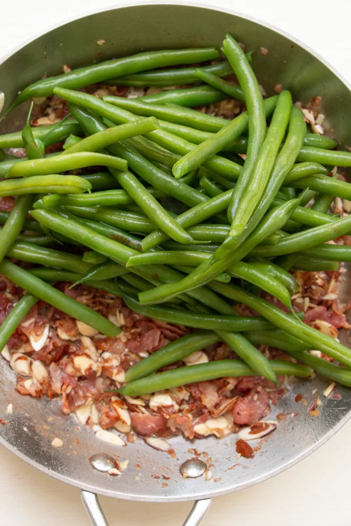 sauté pan with sautéed almond mixture and green beans 