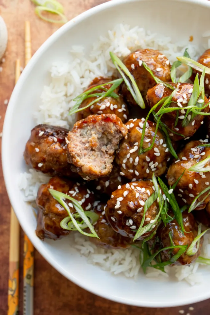 bowl of beef meatballs with teriyaki sauce over rice with green onions 