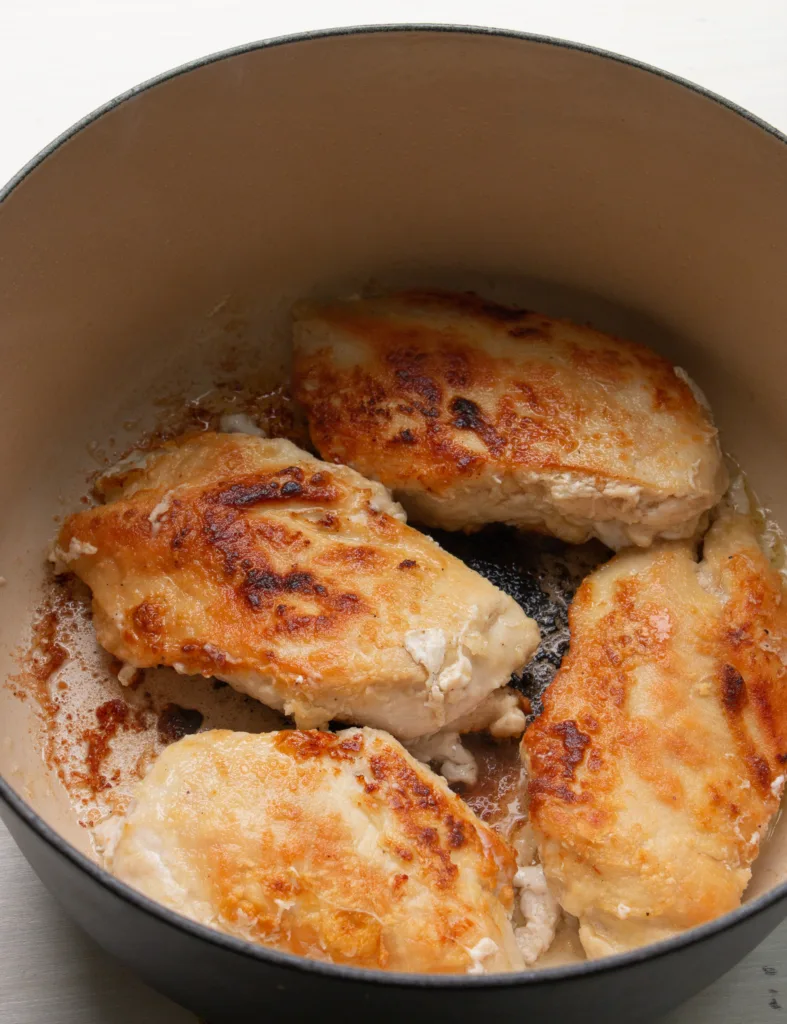 browned chicken cutlets in a Dutch oven