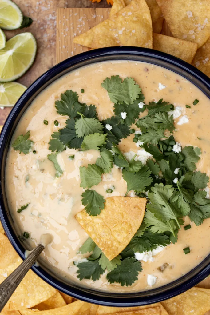 bowl of white queso with cilantro and tortilla chips