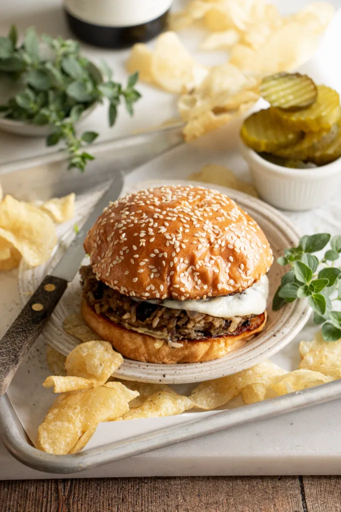 veggie burger on a sheet tray with pickles and chips