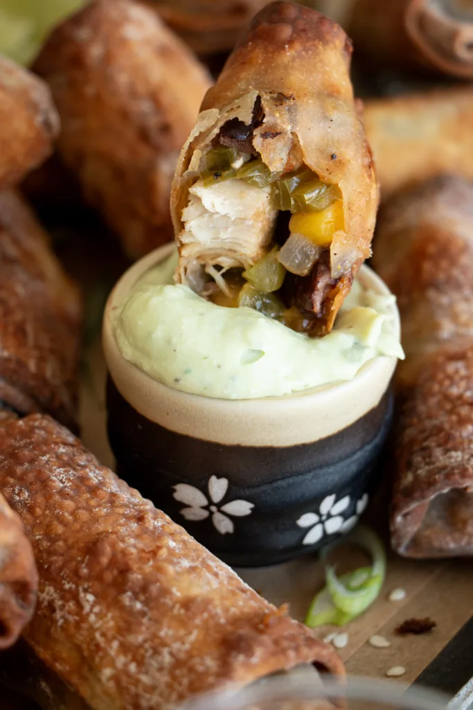egg roll being dipped in avocado crema 