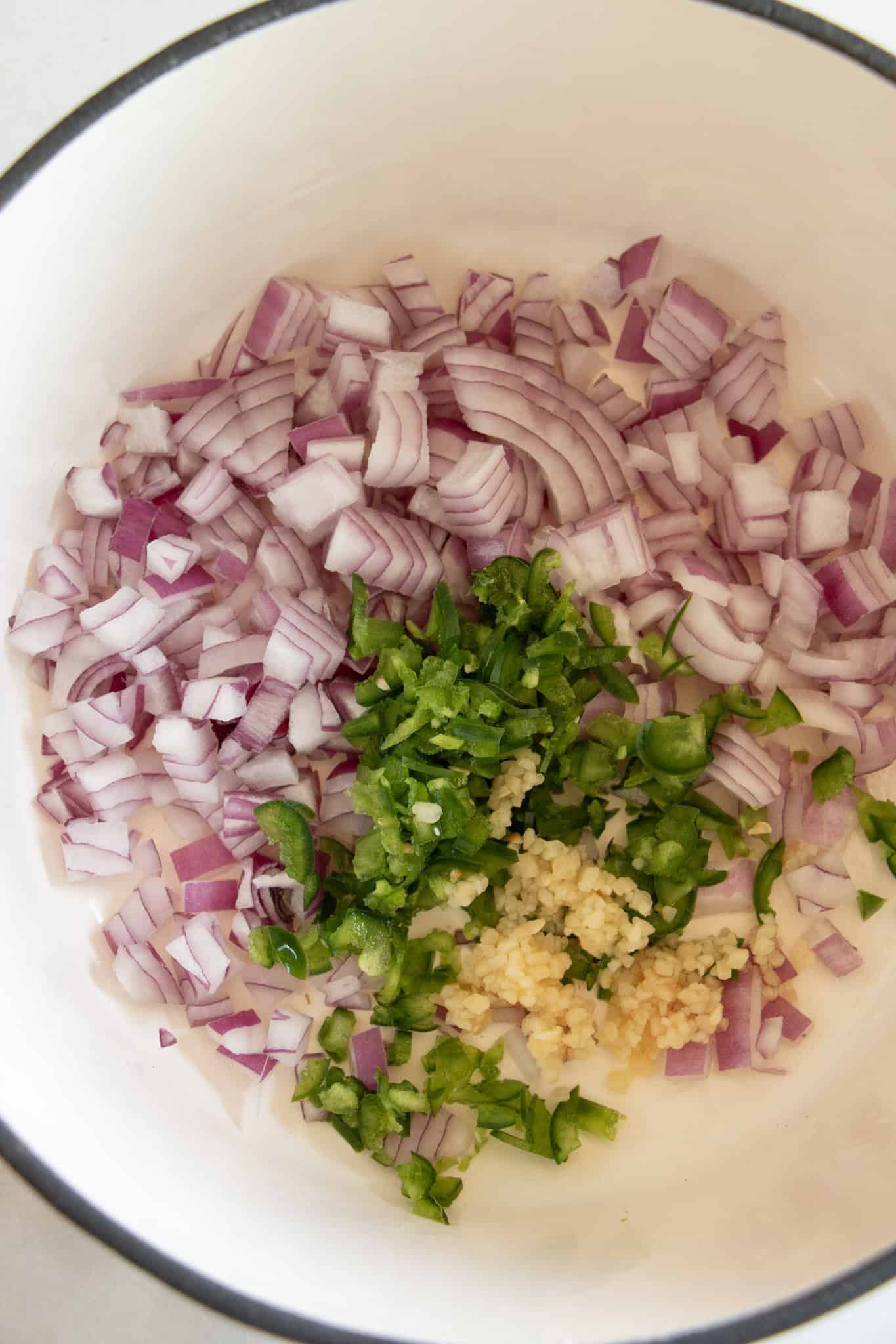 raw onions, jalapenos, and garlic in a pan