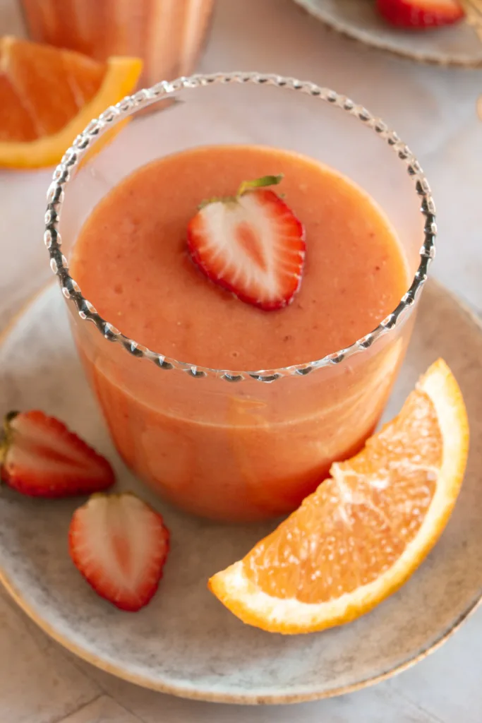 glass of mango smoothie with a fresh strawberry 