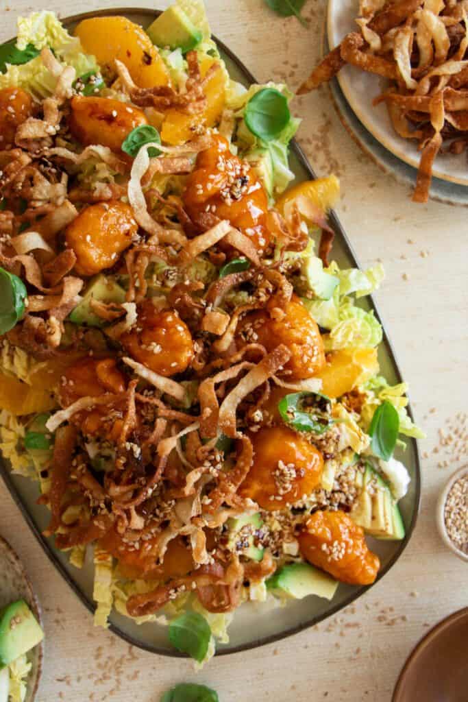 large platter with sesame ginger chicken salad topped with crispy wontons 