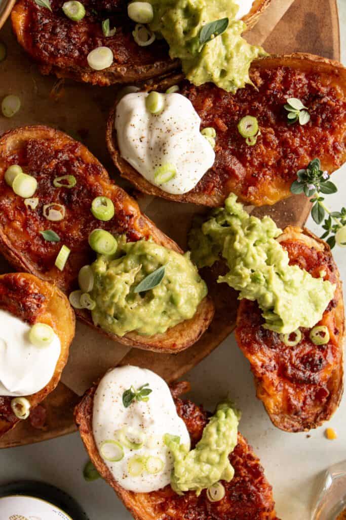 cooked frozen potato skins on a tray with guacamole, sour cream, green onions, and fresh thyme.