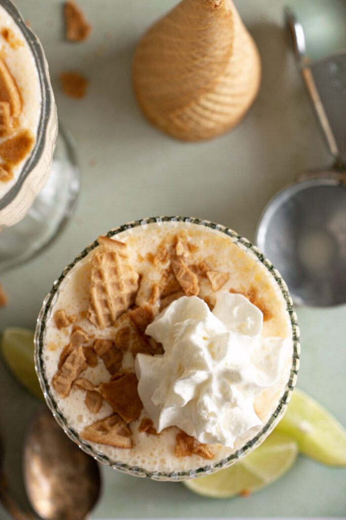 key lime pie shake topped with a dollop of whipped cream and crushed wafer cones 