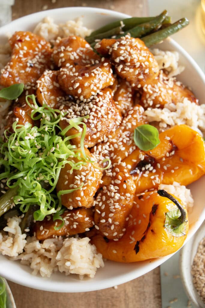 crispy honey chicken in a bowl with green onions 