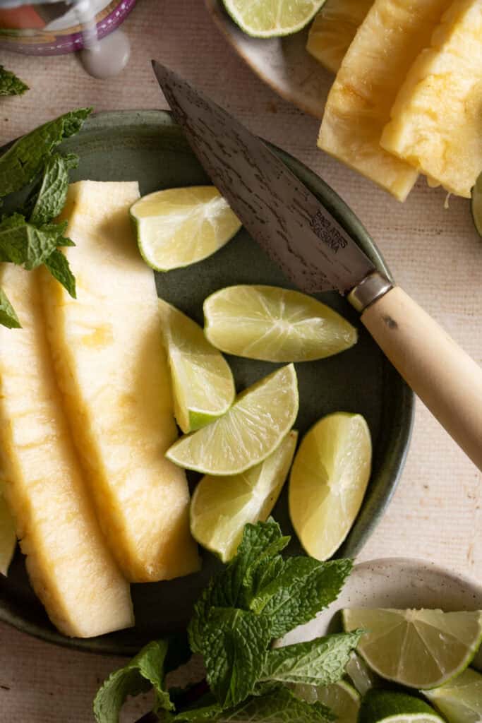 fresh pineapple. limes, and mint on a plate 