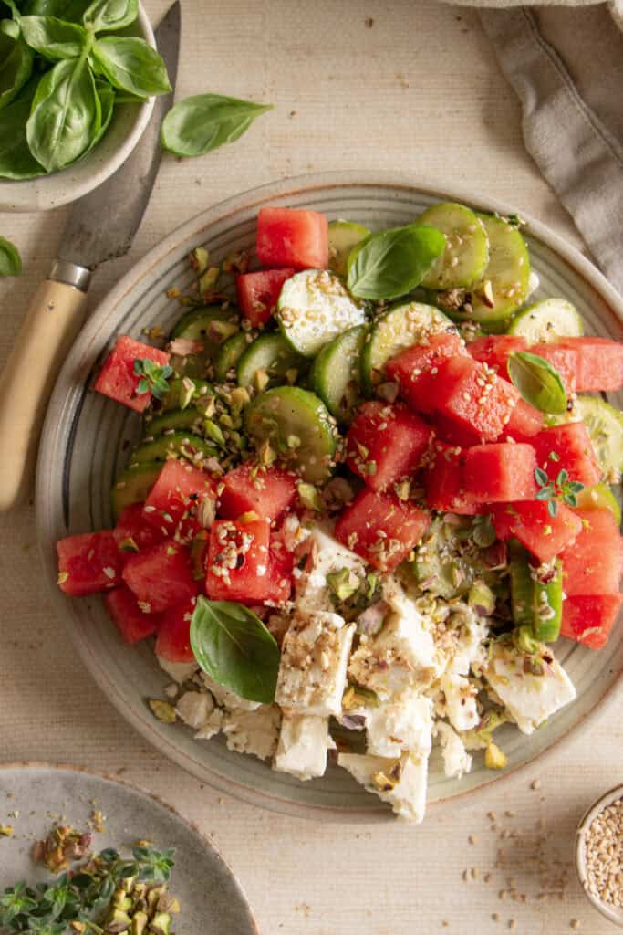 plate with cucumber and watermelon salad topped with fresh basil