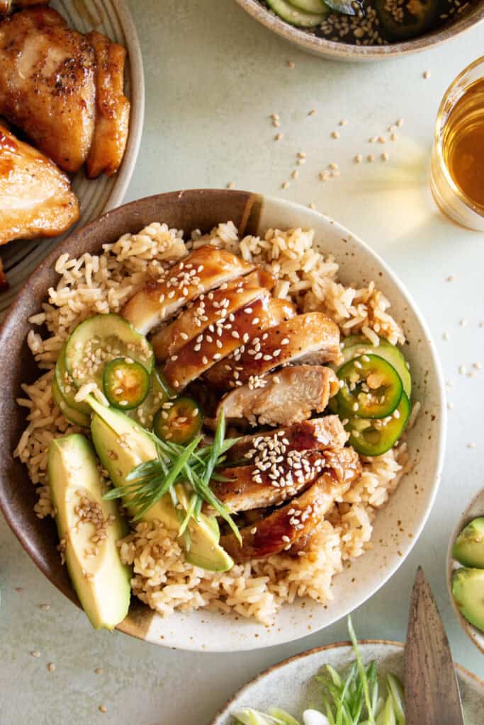 homemade teriyaki chicken in a bowl over rice with cucumber salad