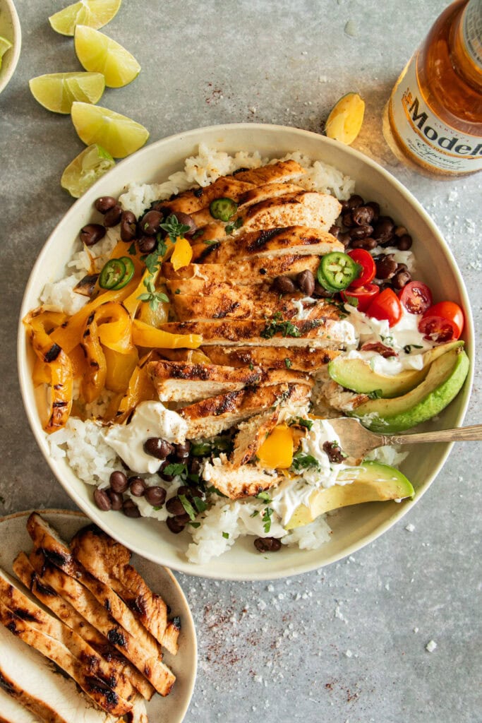 bowl of rice topped with grilled chicken and bell peppers 