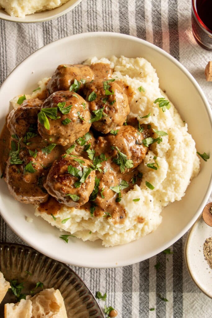 Bowl of mashed potatoes topped with Swedish meatballs and gravy