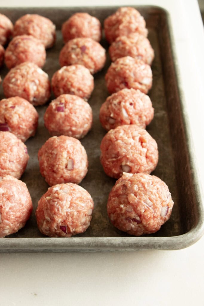 beef and pork meatballs rolled on a sheet pan 