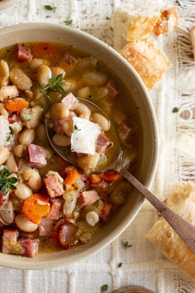 bowl of ha and bean soup with a spoon and baguette 