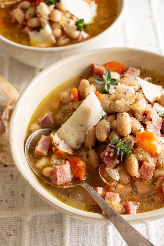 bowls of ham and bean soup on a tablecloth with crusty bread 