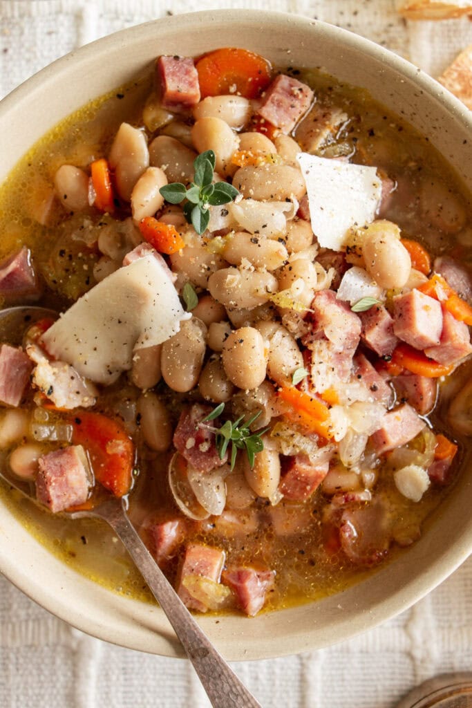 a big bowl of hearty ham and bean soup with parmesan cheese and fresh thyme 