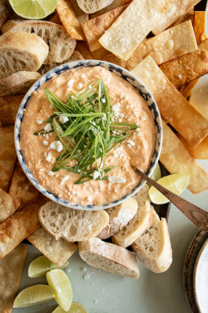 bowl of high protein buffalo chicken dip with green onions and tortilla chips