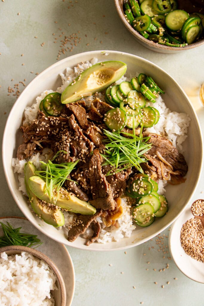 rice bowl with sliced beef and cucumber salad