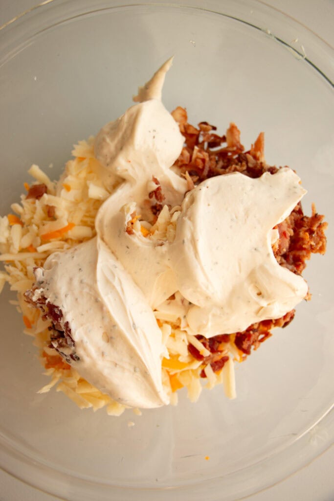 mixing bowl with bacon, shredded cheese, cream cheese, and dip