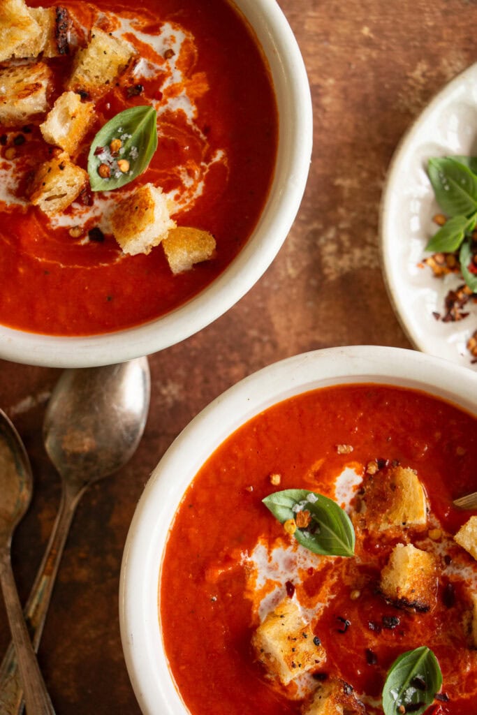 2 bowls of tomato soup with fresh basil and crispy croutons 