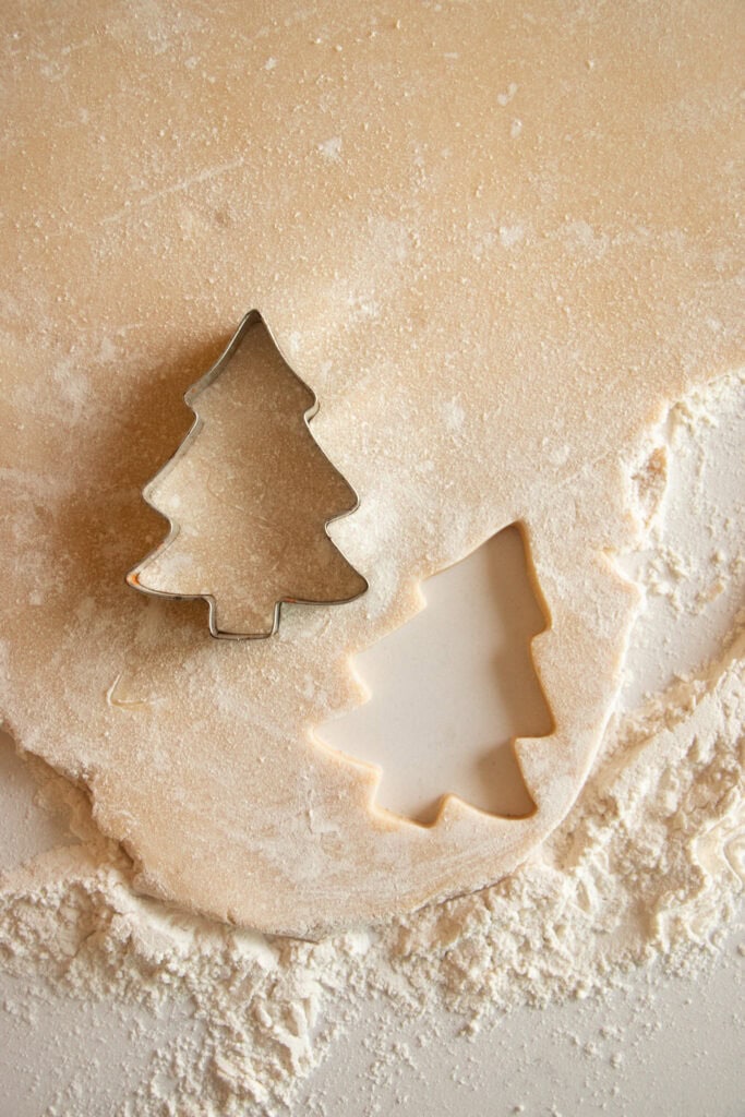 rolled out sugar cookie dough with a Christmas tree cookie cutter