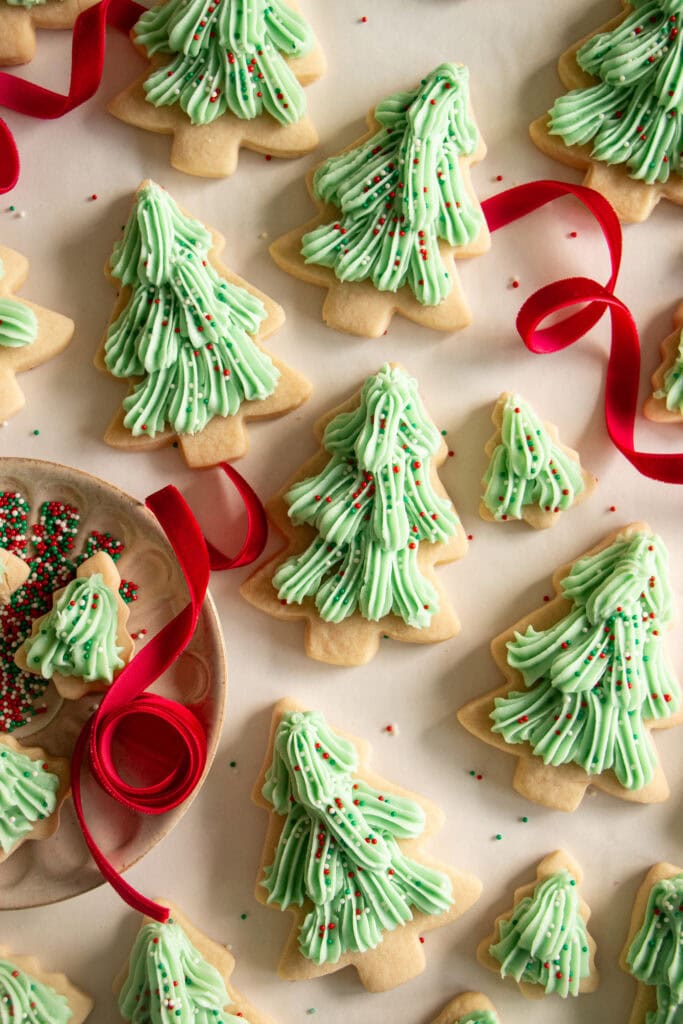 frosted sugar cookies on a sheet of parchment with red ribbon